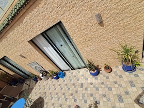 A courtyard with tiled flooring, potted plants, a sliding glass door, and a small table with chairs. - Dar Diaft'na (Marrakech)