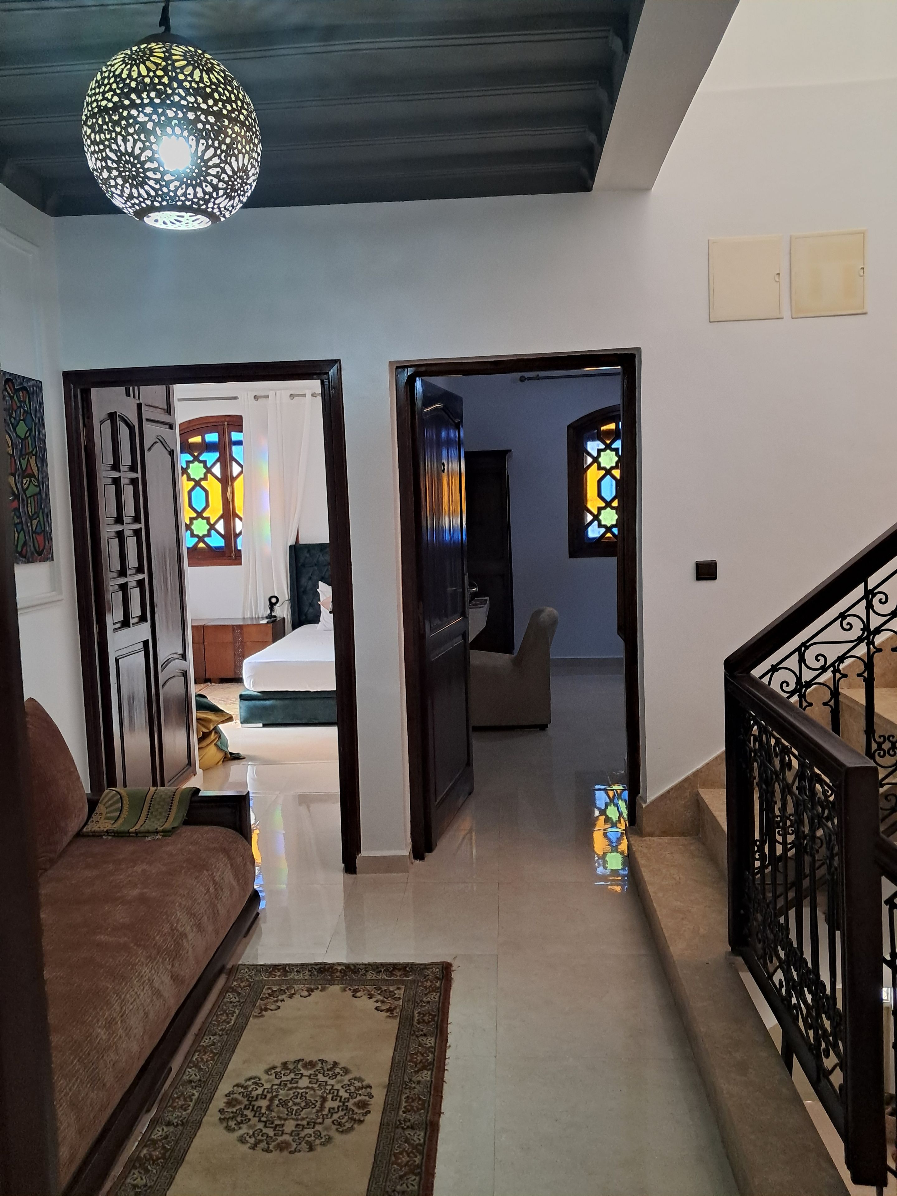A hallway with a sofa, a patterned rug, and a staircase with a railing.