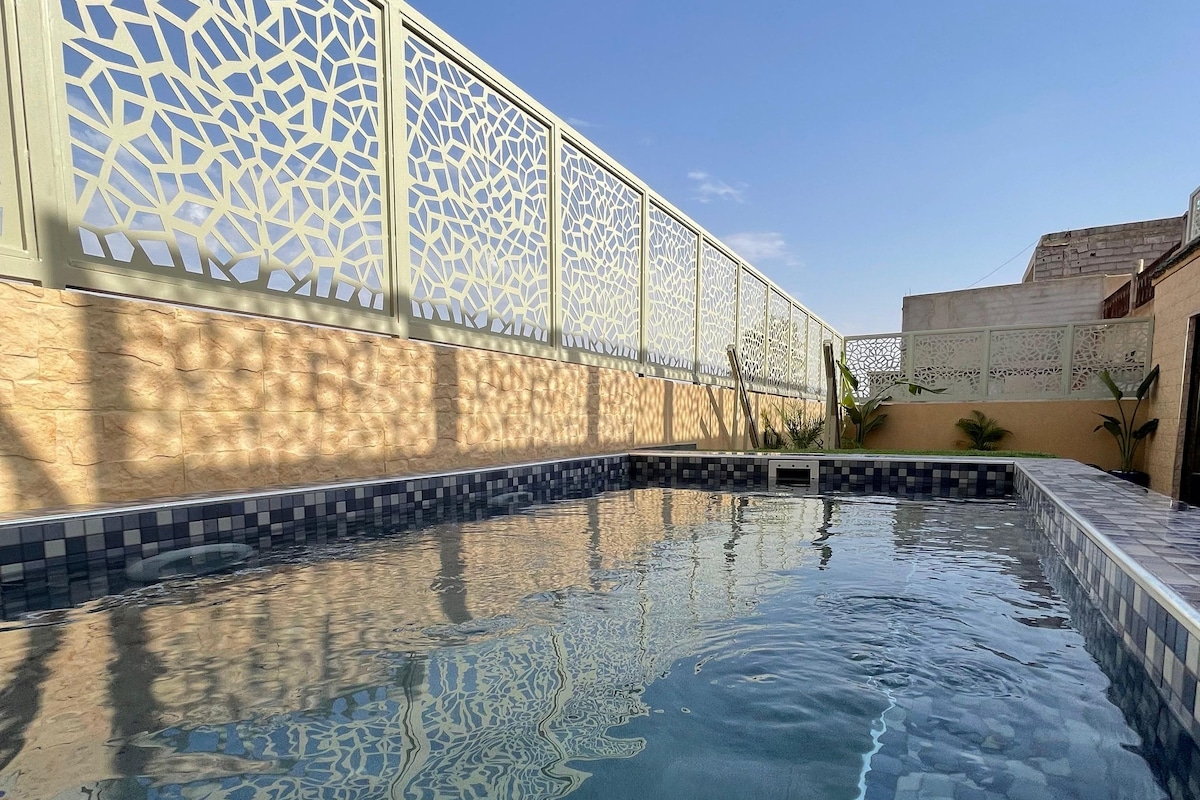 A swimming pool with a geometric tile pattern, surrounded by a wall with a decorative lattice design.
