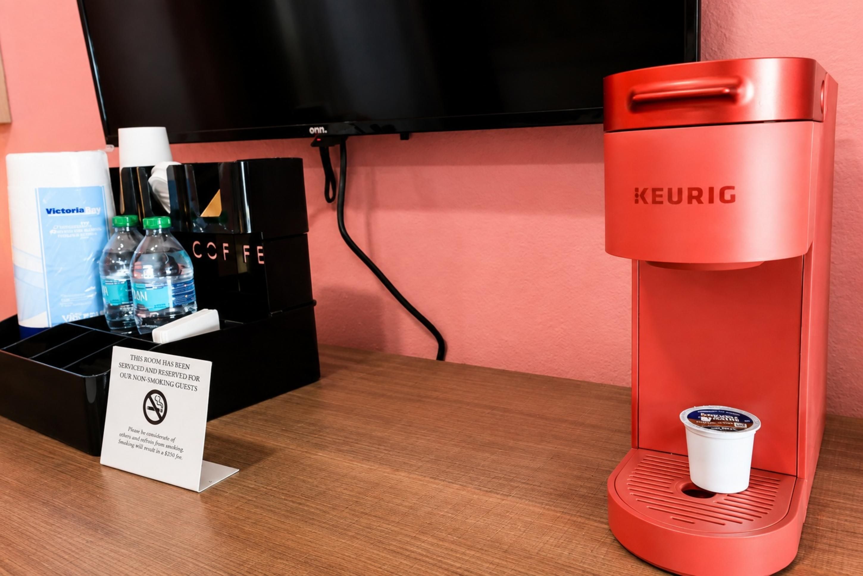 Una cafetera, una botella de agua, una botella de refresco, un artículo con la marca Victoria Bay y un letrero que indica que la habitación es para no fumadores.