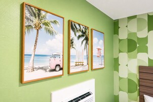 A room with three framed beach-themed pictures on the wall, a white radiator, and a patterned wallpaper.