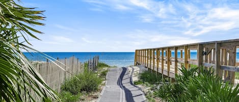 A wooden boardwalk leading to a beach with clear skies.