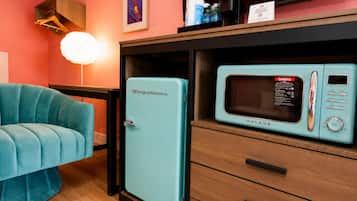 Een kleine keuken met een retro koelkast en een magnetron.