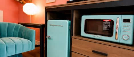 A compact kitchen with a vintage-style refrigerator and a microwave.