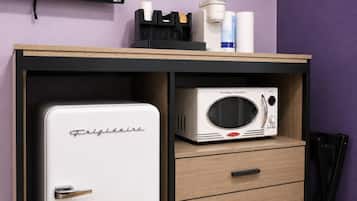 A compact kitchenette with a white refrigerator, a microwave, and a coffee maker on a wooden countertop.