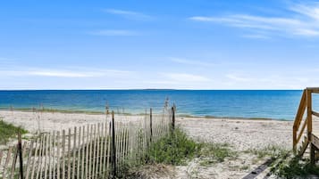 Een strand met een houten omheining en een bankje, dat uitkomt op de oceaan.
