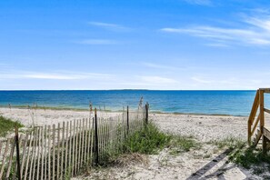 Ein Strand mit Holzlattenzaun und einer Bank, der zum Meer führt.