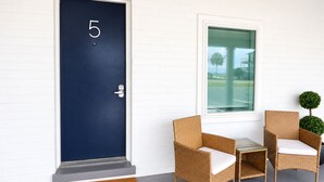 A dark blue door with the number 5, a small table with chairs, and a window with a view of palm trees. - The Blu - A Boutique Motel (Port St. Joe)