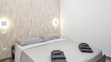Un dormitorio moderno con cama, dos lámparas de noche, aire acondicionado instalado en la pared y suelo de madera.