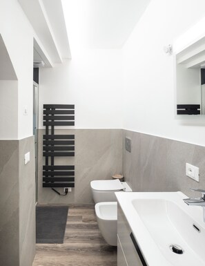A modern bathroom with a toilet, bidet, and a large sink. - Vrbo Property (Montichiari)