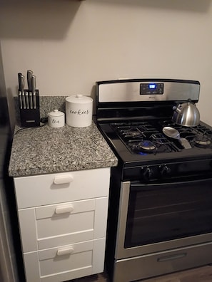 Une cuisine équipée d’une cuisinière, d’une bouilloire et d’un récipient étiqueté « thé ».