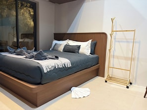 A modern bedroom with a large bed, a wooden headboard, and a gold storage unit.