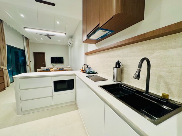 A modern kitchen with a central island, built-in microwave, and stainless steel sink.