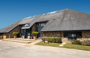 A modern building with a sloped roof, stone facade, and multiple windows.