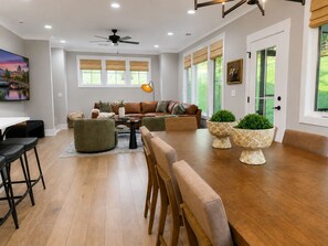 A modern living room with a brown leather sofa, green armchairs, a wooden dining table, and potted plants. - Paris Mountain Haven (Greenville County)