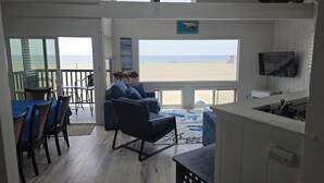 Ein Zimmer mit Meerblick, inklusive Fernseher und einem Essbereich mit Stühlen und Tisch.