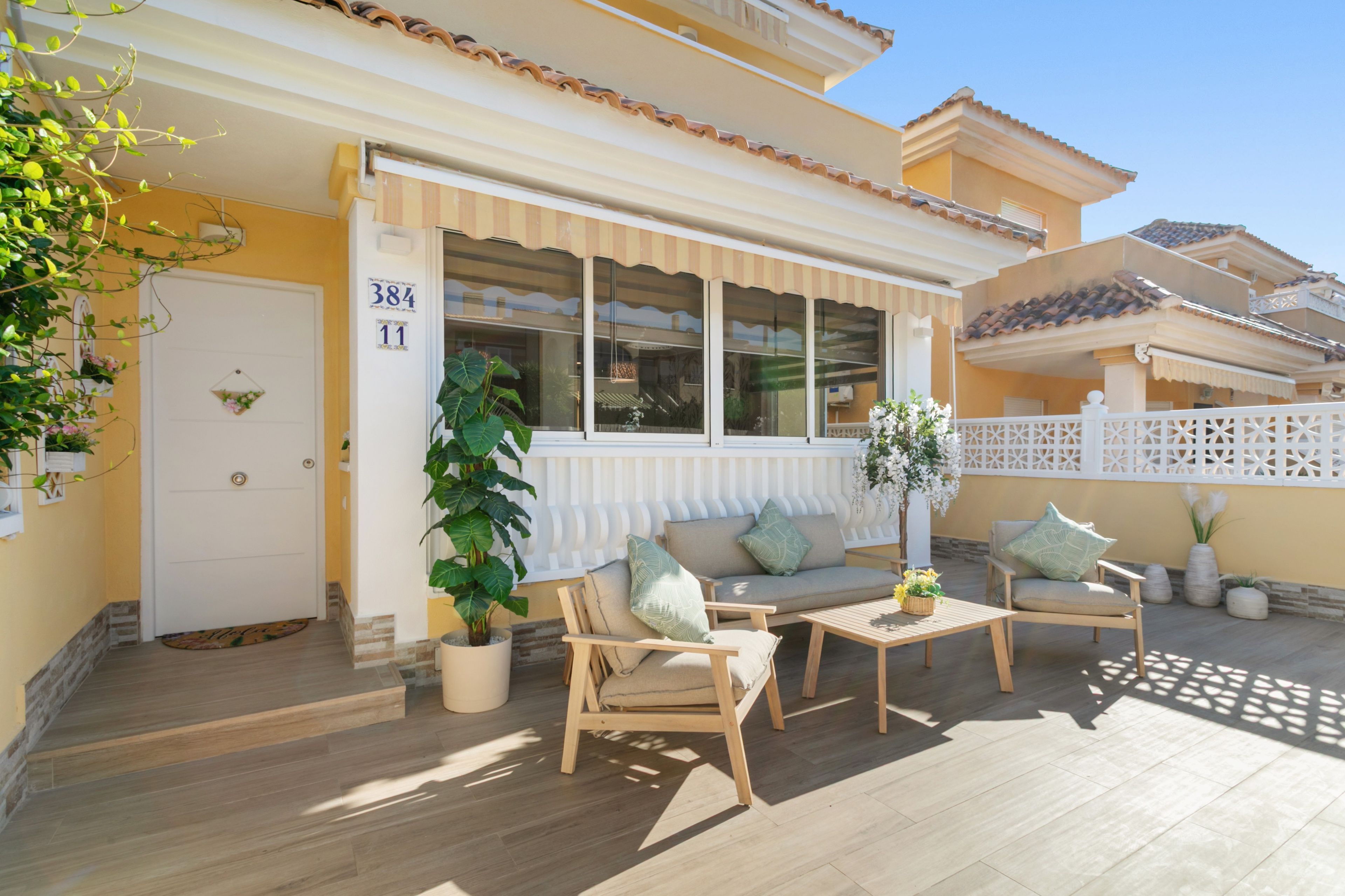 Propiedad residencial con un patio cubierto, asientos exteriores y una planta en maceta.