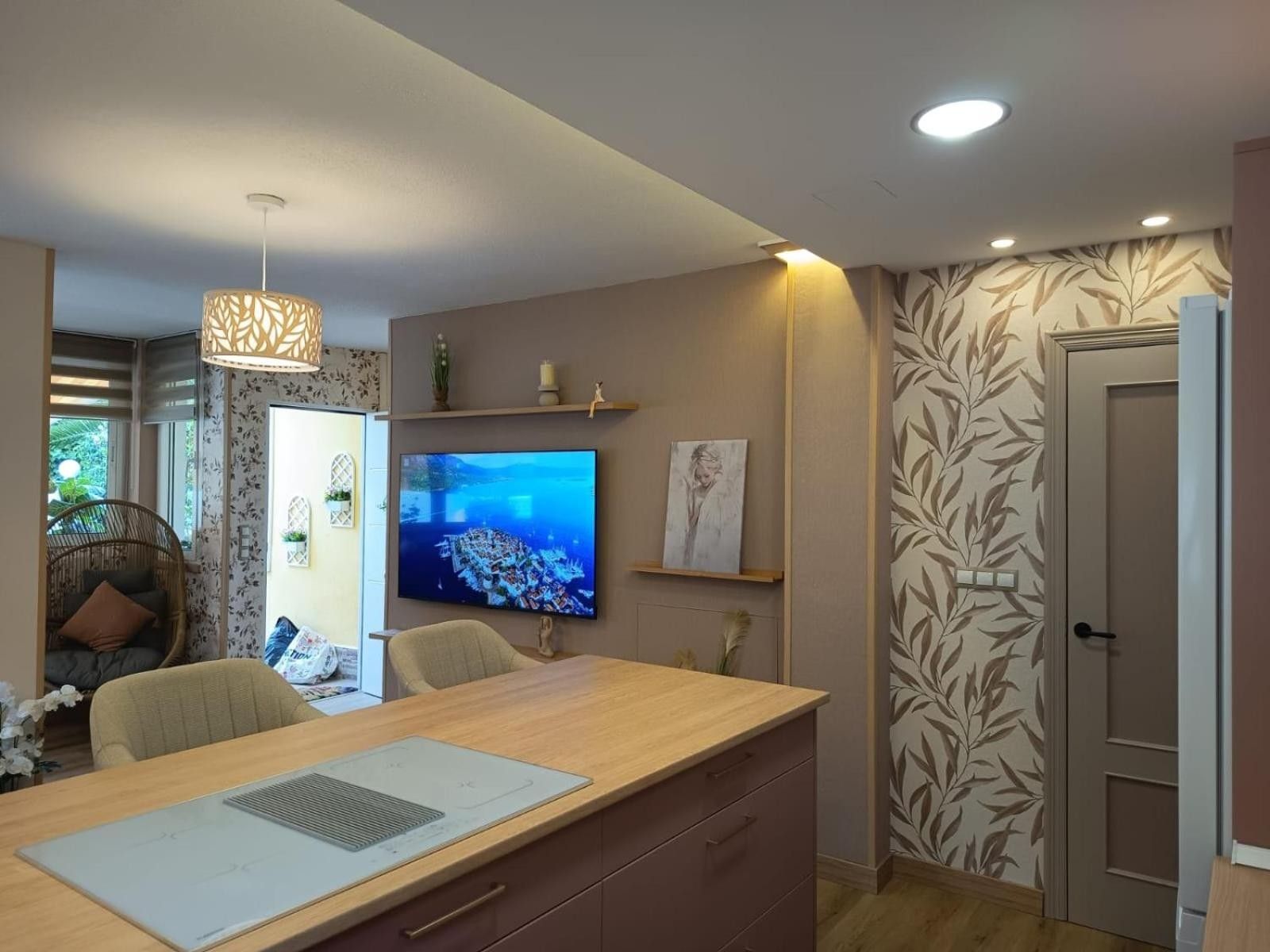 Una cocina moderna con encimera de madera, microondas integrado y un televisor de pantalla plana grande montado en la pared.