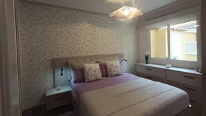 Une chambre à coucher avec un lit, des tables de chevet, une fenêtre et un luminaire au plafond.
