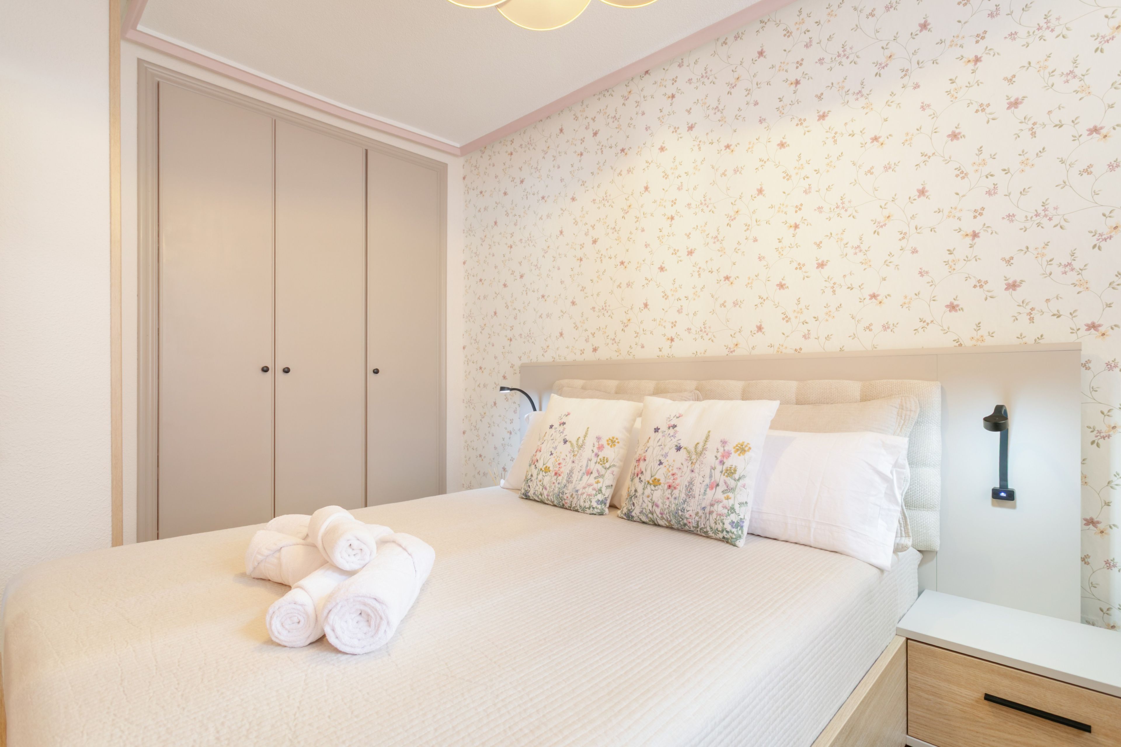 A bedroom with a bed, a nightstand, a lamp, and a wardrobe.