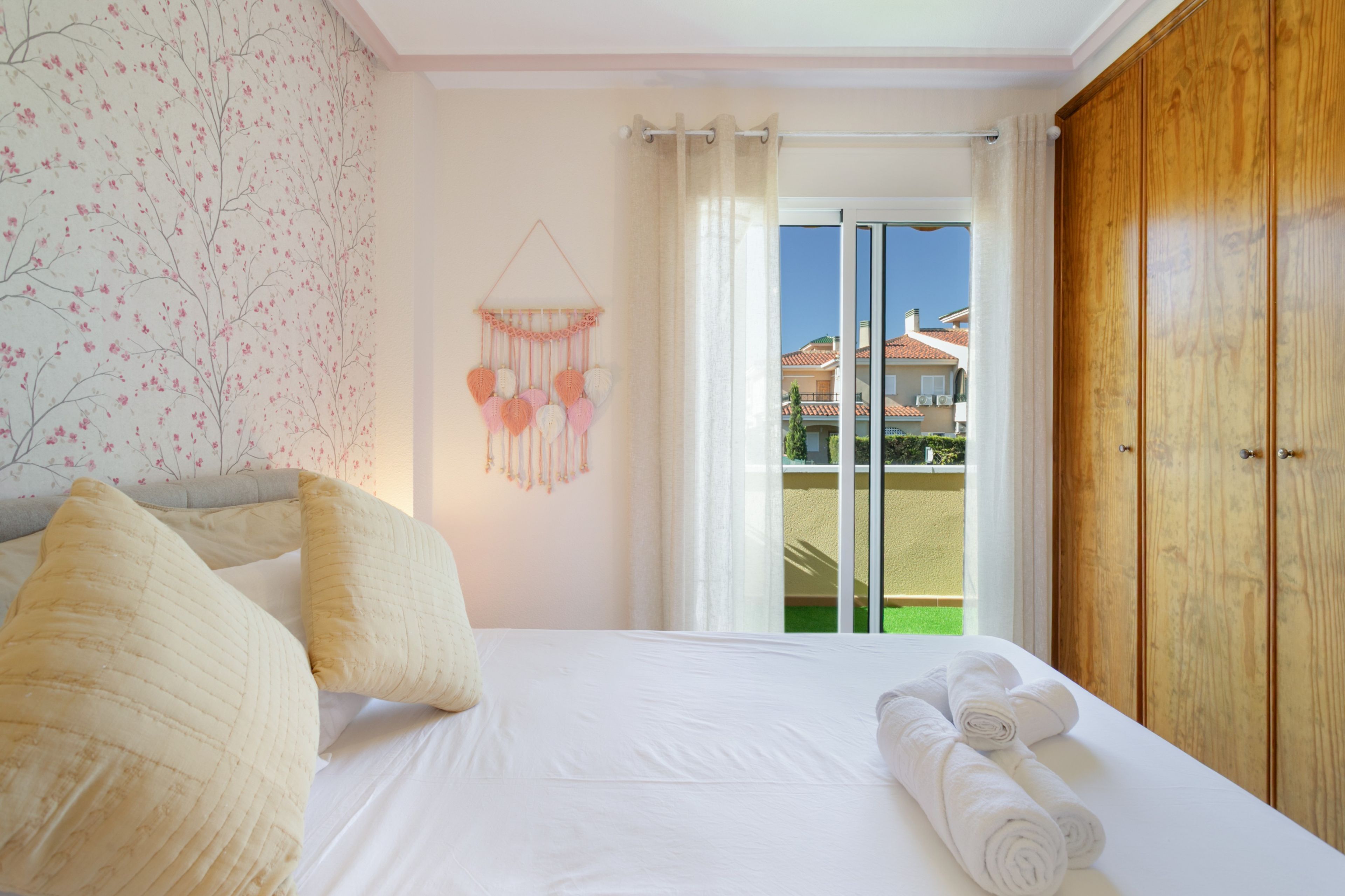Camera d'albergo con un letto, cuscini, un quadro appeso al muro e vista sull'esterno.