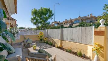 Un patio con mobiliario exterior, un cerco decorativo y un cartel que indica el nombre de la propiedad.