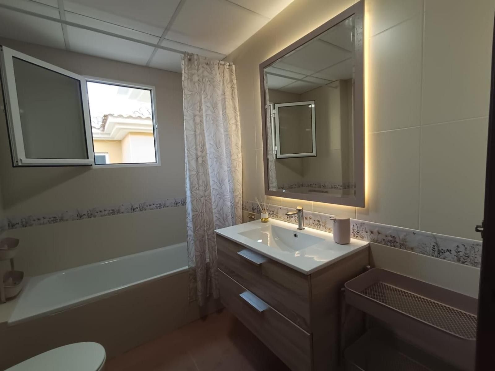 Een badkamer met een bad, een wastafel met spiegel en een toilet.