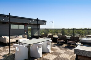 A rooftop terrace with a modern outdoor seating area, including a sofa and chairs, and a table. - Ruby Junction (Atlanta)