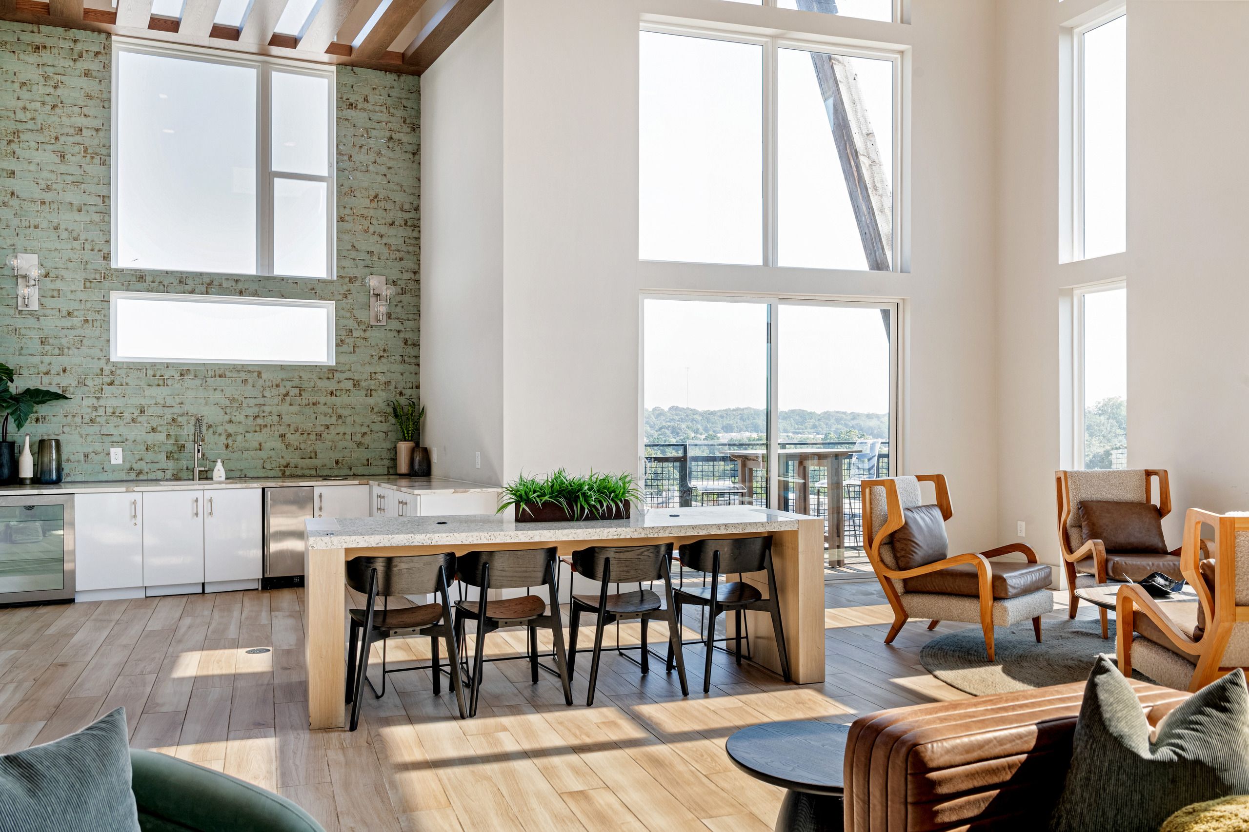 A spacious living area with a dining table, multiple chairs, and a view of the outdoors through large windows.
