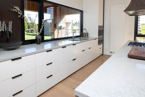 A modern kitchen with a large window, white cabinetry, and a built-in stove. - FASSWAY FARM - LUXURIATE IN STYLE, TEN MINUTES TO KYNETON (Greenhill)