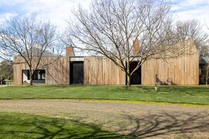 Un bâtiment moderne avec une façade en bois, de grandes fenêtres et une pelouse verdoyante.