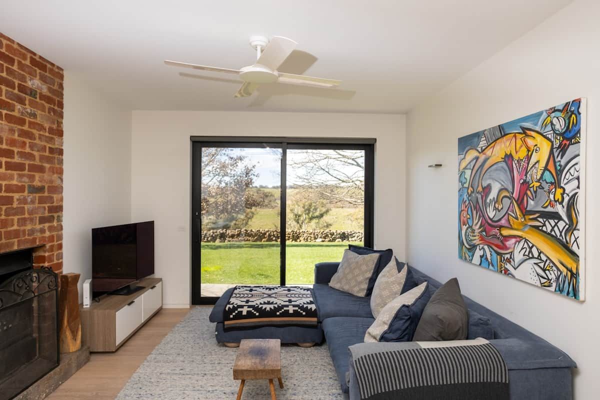 Ein modernes Wohnzimmer mit Kamin, großem Fenster, einer Couch und einem Gemälde.