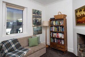 A living room with a sofa, a bookshelf, and a fireplace. - FASSWAY FARM - LUXURIATE IN STYLE, TEN MINUTES TO KYNETON (Greenhill)