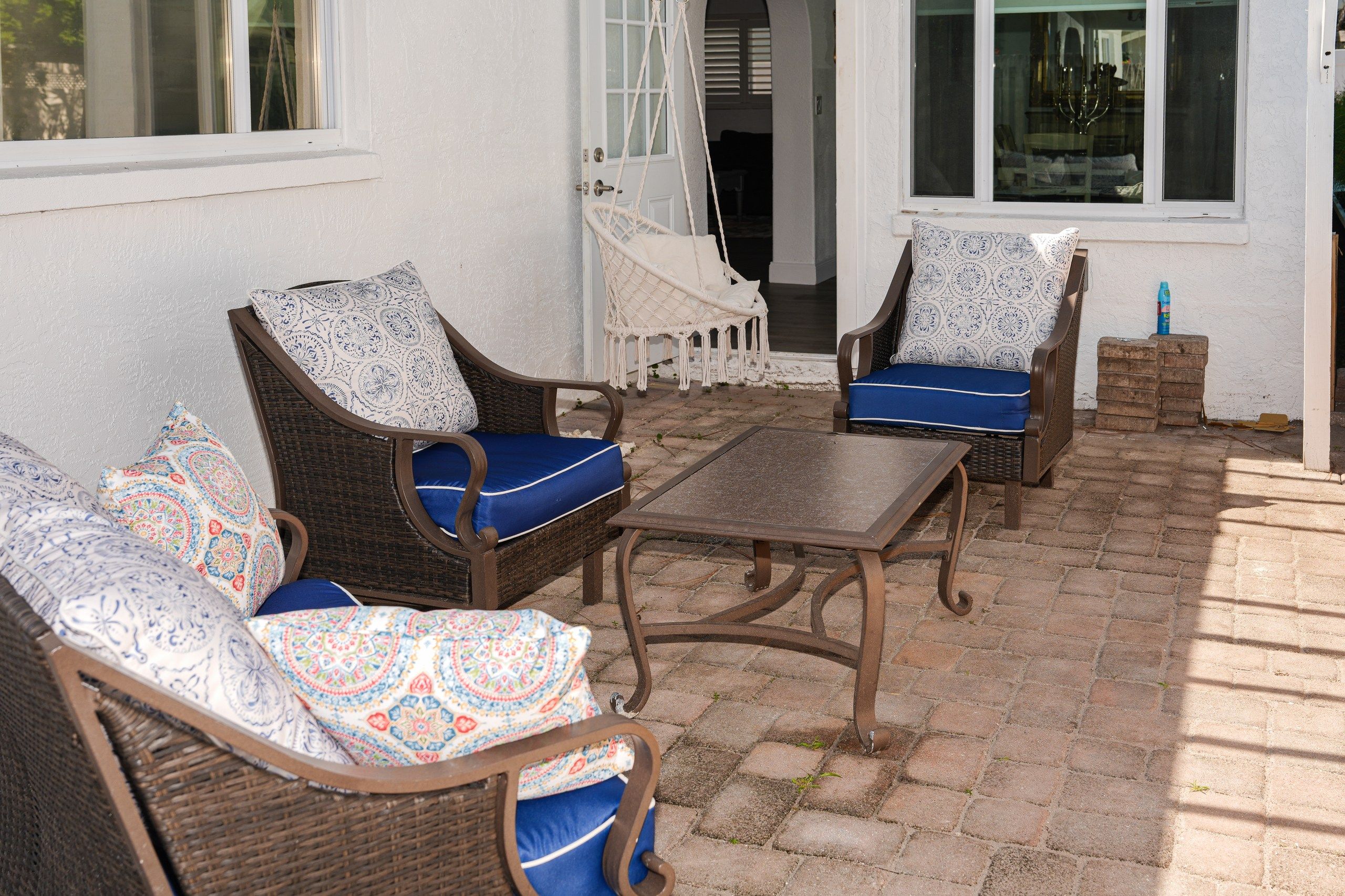 Un patio con mobiliario de mimbre, incluyendo dos sillas y una mesa.