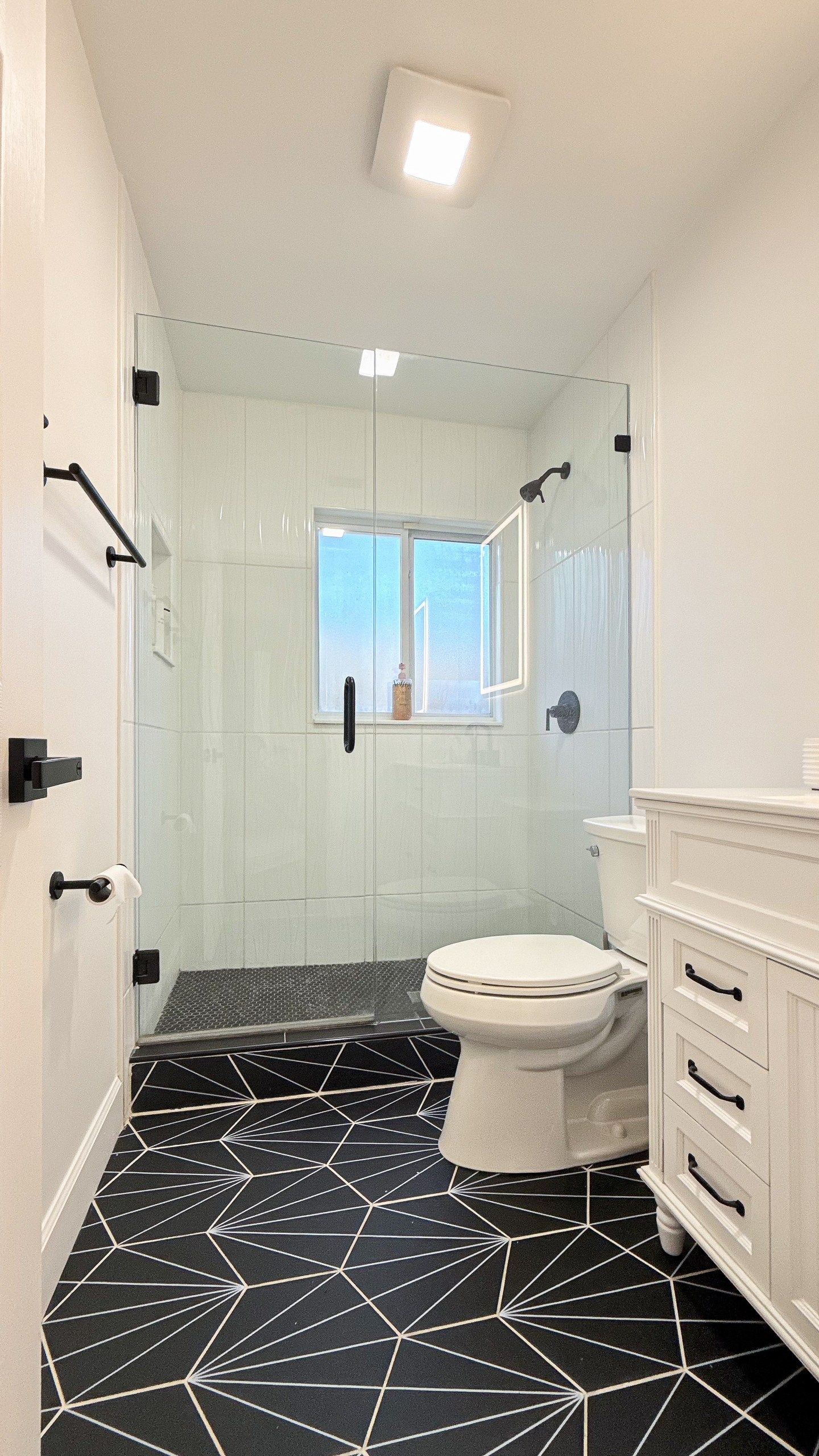 A bathroom with a toilet, a shower, and a window.
