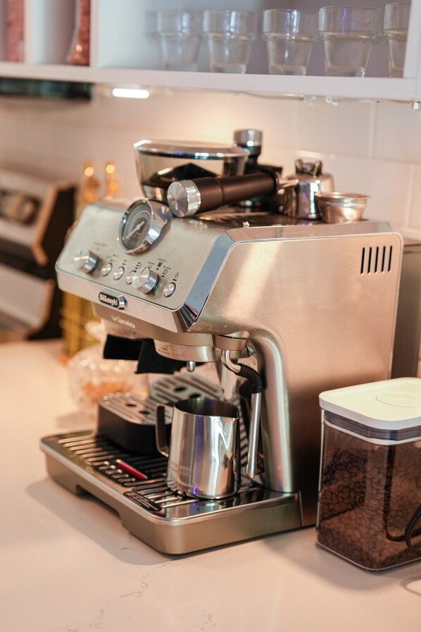 A coffee machine with a portafilter, a milk frother, and a container of coffee beans.