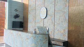 Een receptiebalie met een marmeren afwerking, een ventilator aan de muur en een decoratief plaquette.