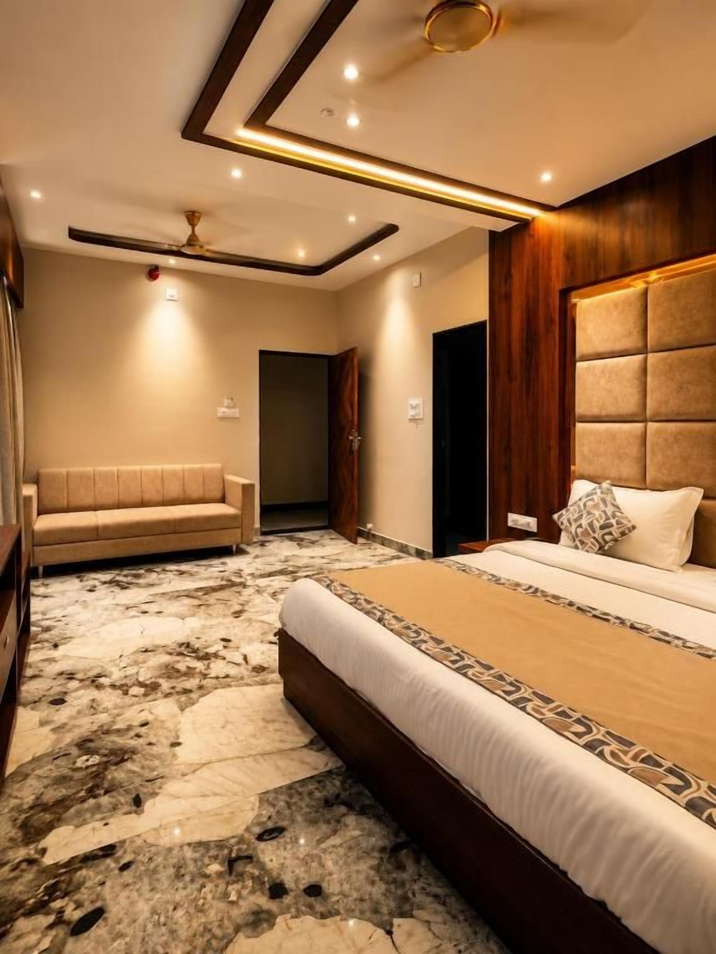 Une chambre d’hôtel avec un grand lit, un canapé, un sol en marbre et une tête de lit en bois.