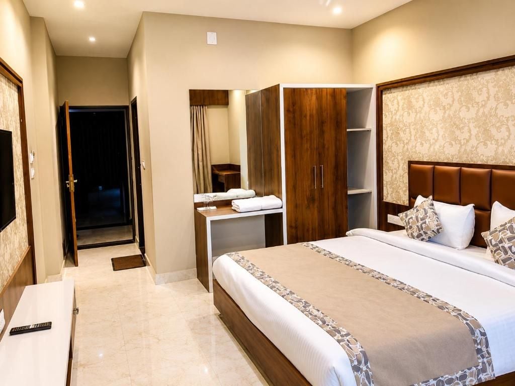 A hotel room with a bed, a wardrobe, a desk, and a television.