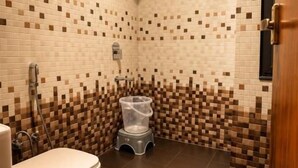 A bathroom with a toilet, shower, and a small stool. - The Lalan Palace (Udaipur)