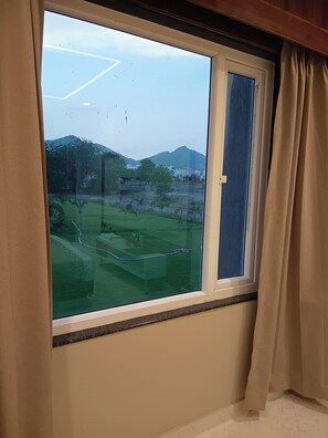 Una ventana con vistas a un paisaje verde, que incluye árboles y una colina.