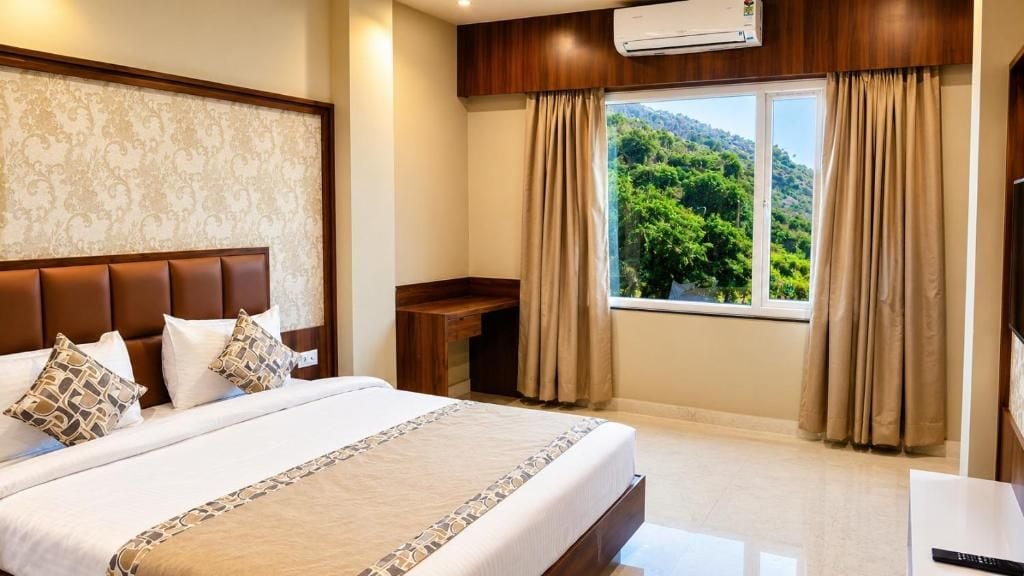 Une chambre d’hôtel avec un grand lit, un bureau et une fenêtre avec des rideaux.