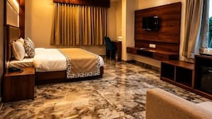 A hotel room with a bed, a TV, a ceiling fan, and a marble floor. - The Lalan Palace (Udaipur)