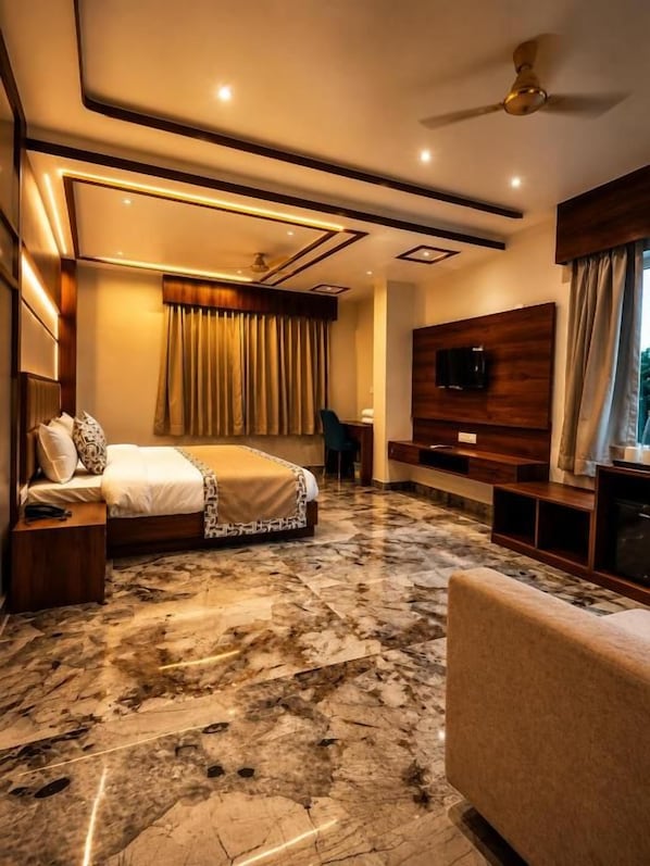 A hotel room with a bed, a TV, a ceiling fan, and a marble floor. - The Lalan Palace (Udaipur)