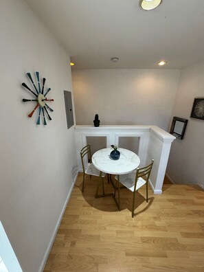 Un comedor con una mesa redonda y sillas, un reloj decorativo en la pared y una repisa blanca sobre la chimenea.