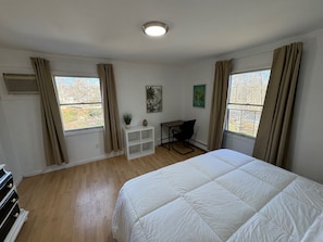 A bedroom with a bed, a desk, and a chair. There are windows with curtains, a ceiling light, and a wall-mounted air vent. - Cozy 1-bedroom apartment in perfect Hillsdale with AC (Hillsdale)