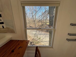 A room with a wooden table and a window overlooking a tree-lined area. - Cozy 1-bedroom apartment in perfect Hillsdale with AC (Hillsdale)