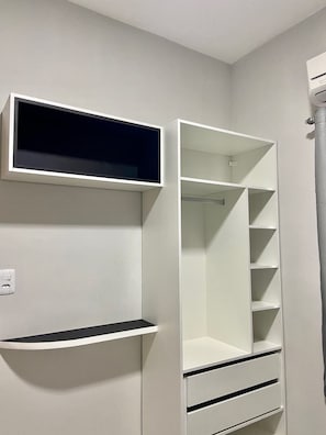 Un placard blanc avec des étagères et des tiroirs, un miroir et une tringle pour suspendre les vêtements.