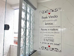 Une salle de bain dotée d’une douche à parois de verre et d’un panneau décoratif portant un message.