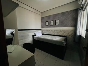 Ein gemütliches Schlafzimmer mit Bett, einem kleinen Nachttisch, einem Spiegel und einer Wand mit dekorativen Fliesen.
